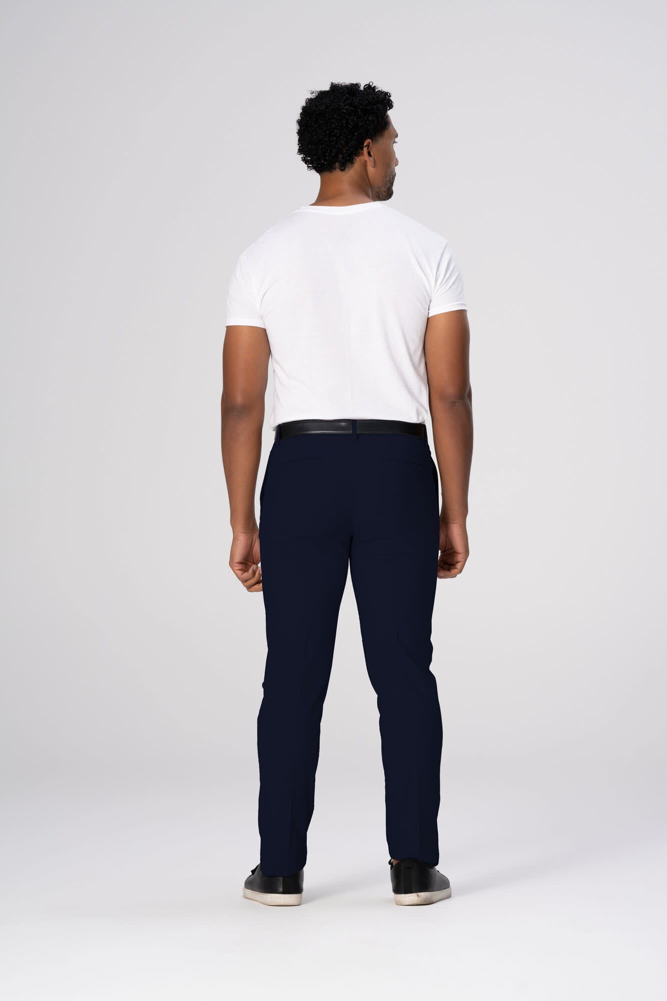 A man wearing navy blue Chino men's poly stretch pants, viewed from the back, paired with a white t-shirt.