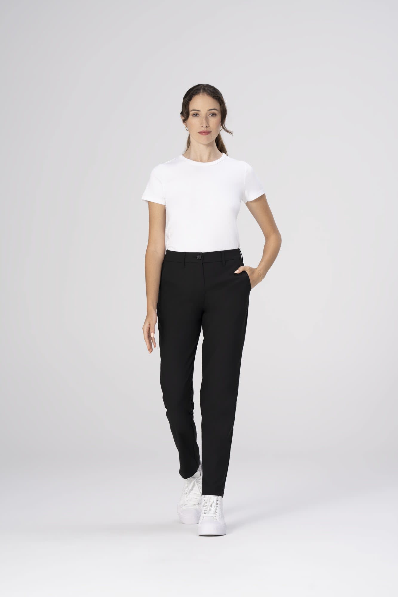A model wearing black poly stretch pants paired with a white t-shirt and white sneakers.