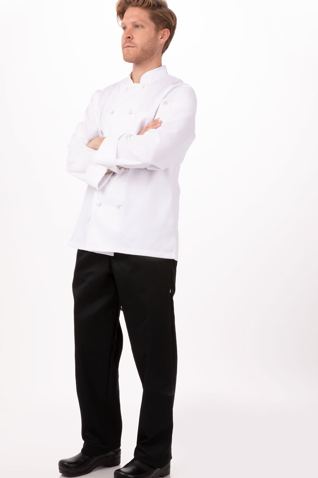A chef jacket in white, paired with black chef trousers, worn by a model standing confidently. Features a logo.