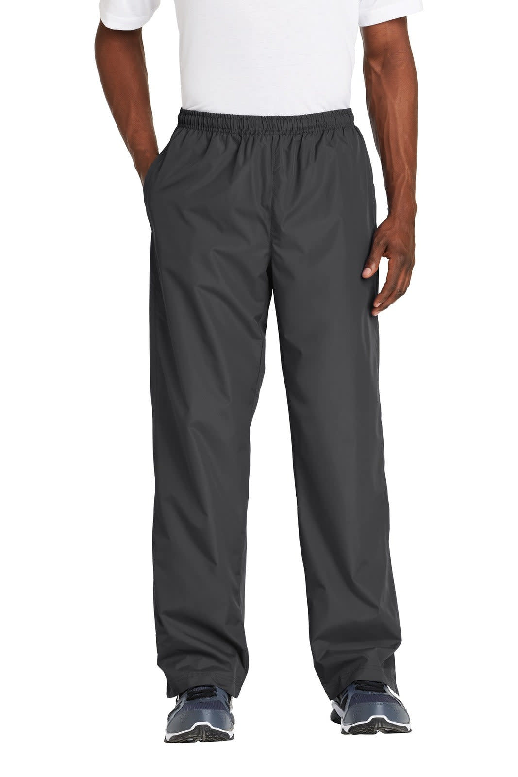 A pair of grey Sport-Tek wind pants standing upright on a model, featuring an elastic waistband and pockets.