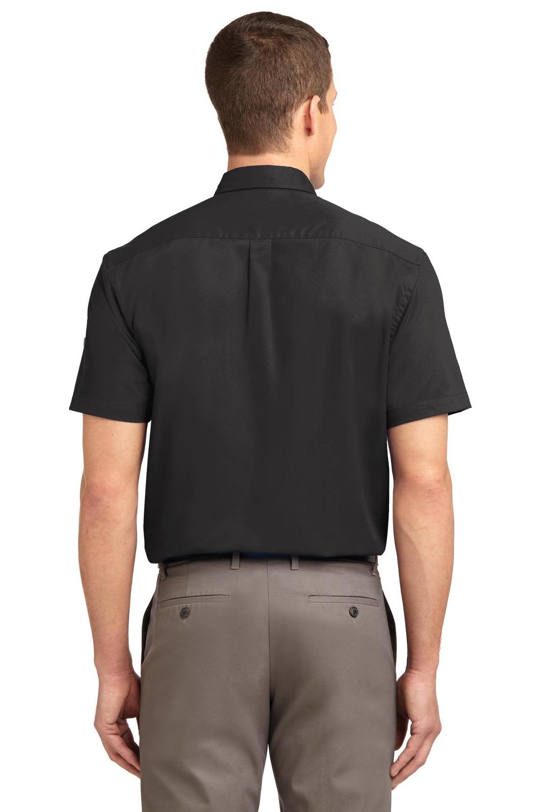 A back view of a short sleeve black button-up shirt being worn with light-coloured trousers. The shirt has a logo.