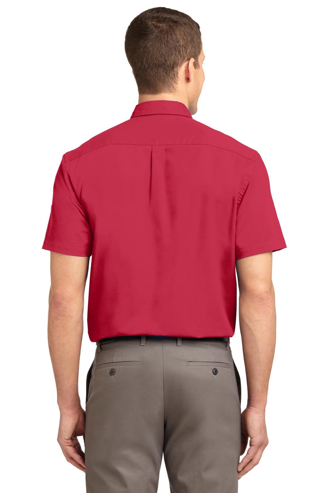 A red short sleeve button-up shirt with a collar, featuring a logo on the back and paired with grey trousers.