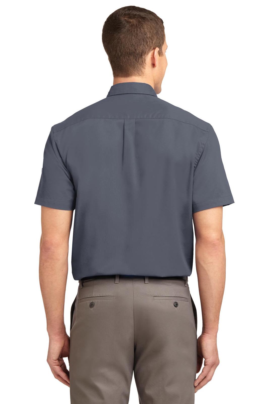 A man wearing a navy short sleeve button-up shirt, viewed from the back, paired with light-coloured trousers.