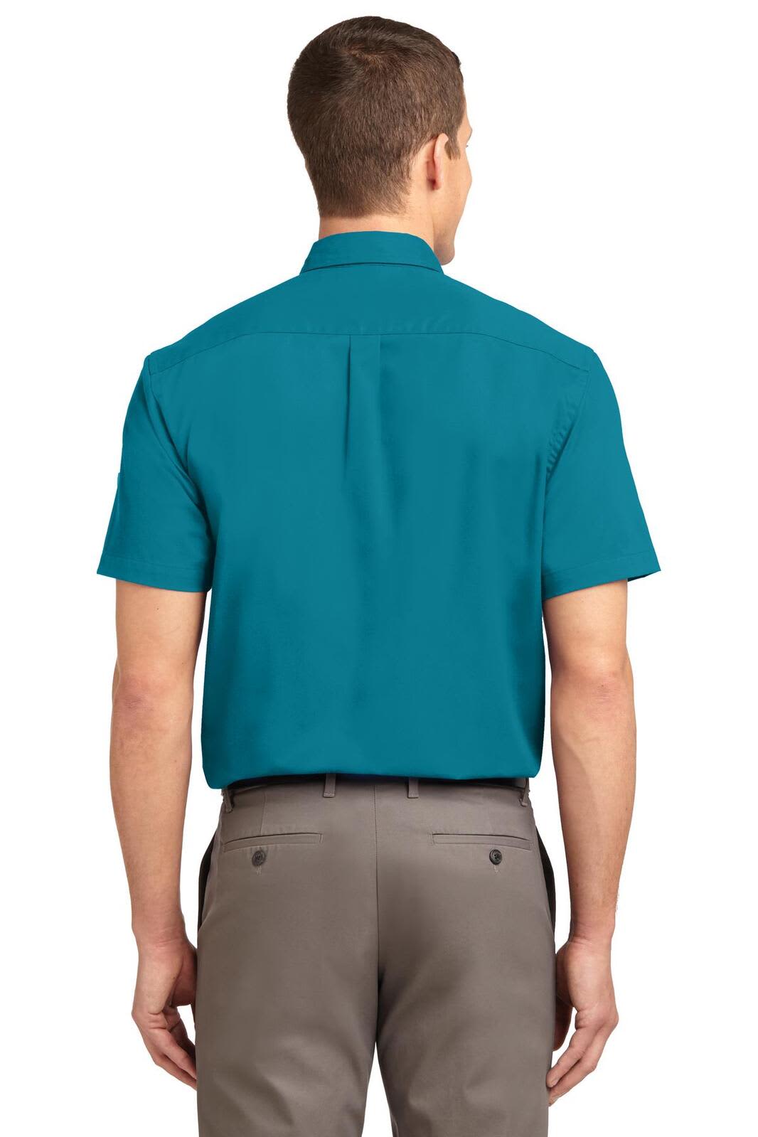 A back view of a men's short sleeve button-up shirt in teal, paired with grey pants, featuring a logo.