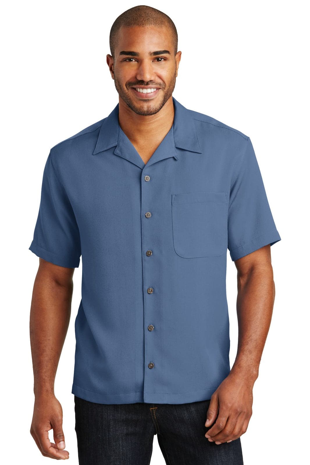 A man wearing a short-sleeved, blue button-up camp shirt with a pocket and a logo.