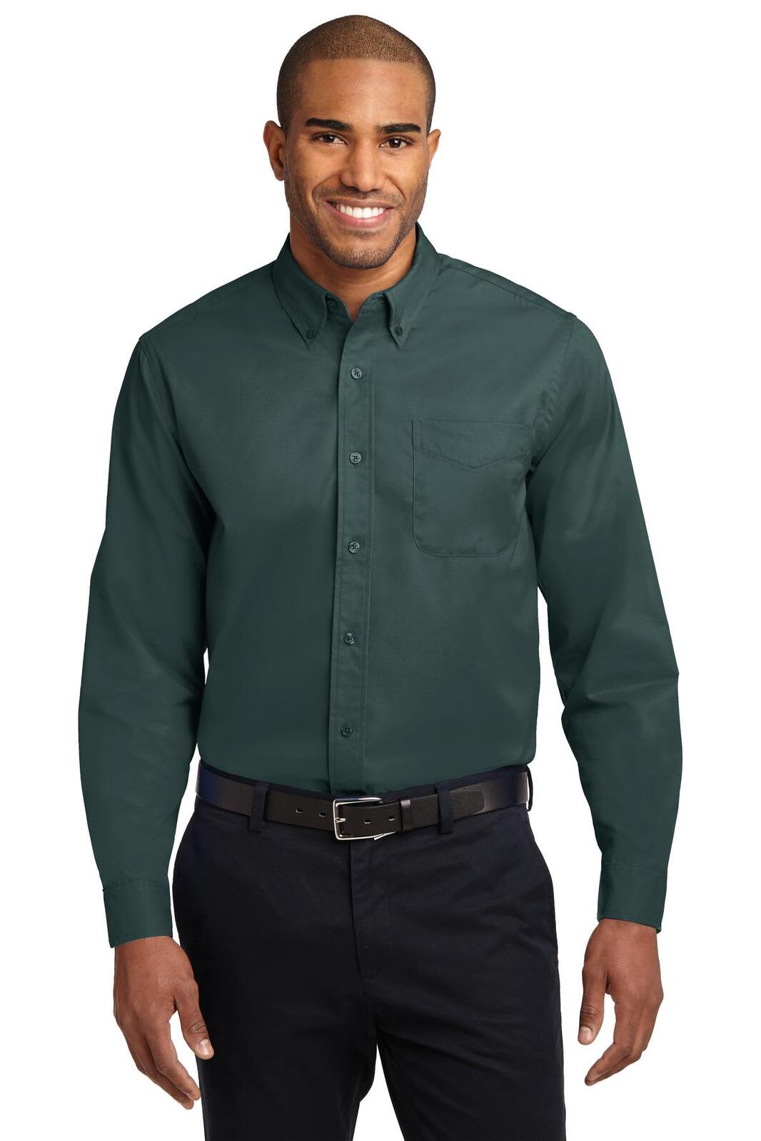 A man models a long sleeve button-up shirt in dark green, featuring a pocket and a logo on the chest.