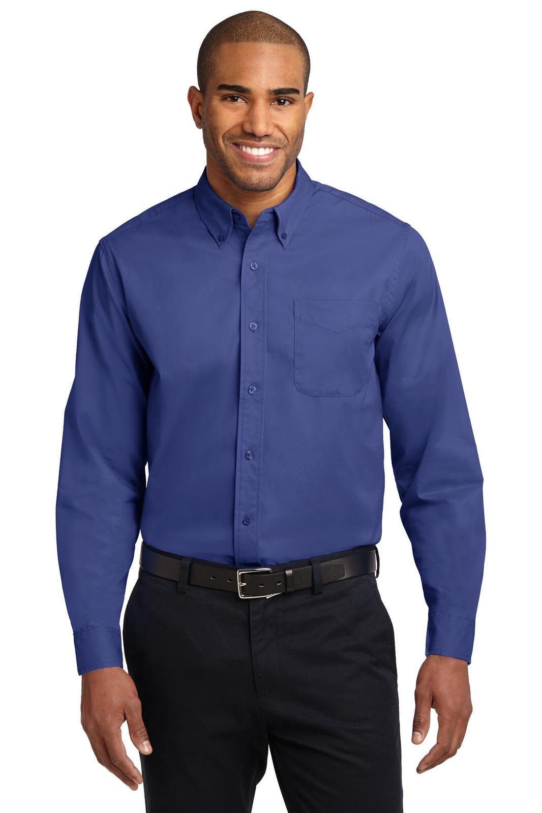A man wearing a long sleeve, blue button-up shirt with a pocket and a belt, standing against a neutral background.