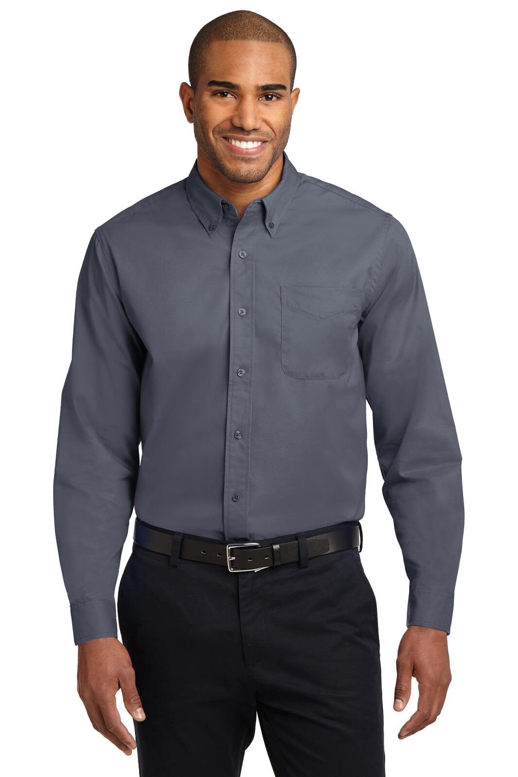 A man wearing a grey long sleeve button-up shirt with a pocket and a black belt, smiling against a neutral background.