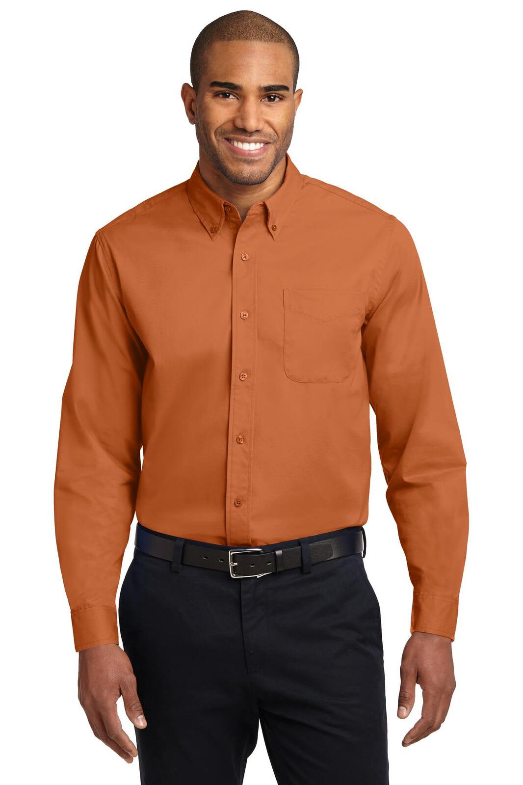 A man is wearing an orange long sleeve button-up shirt with a pocket, paired with dark trousers.