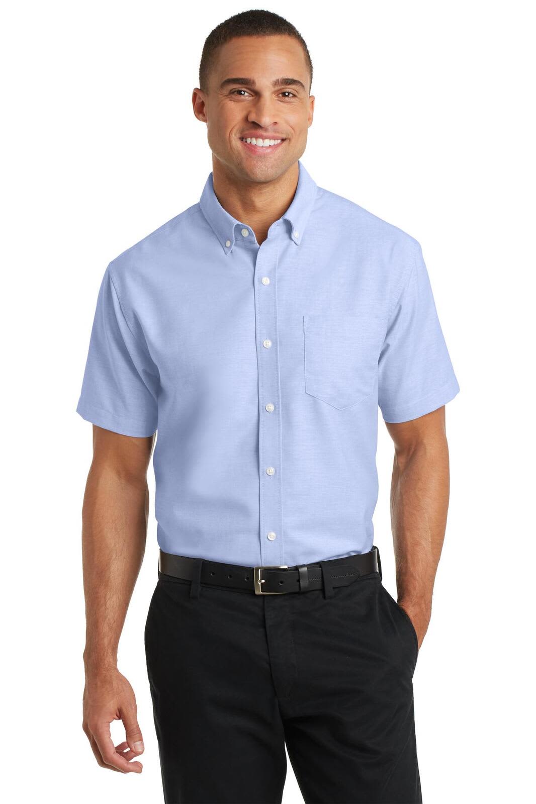 A light blue short sleeve button-up shirt with a pocket and a brand logo, worn by a smiling man.