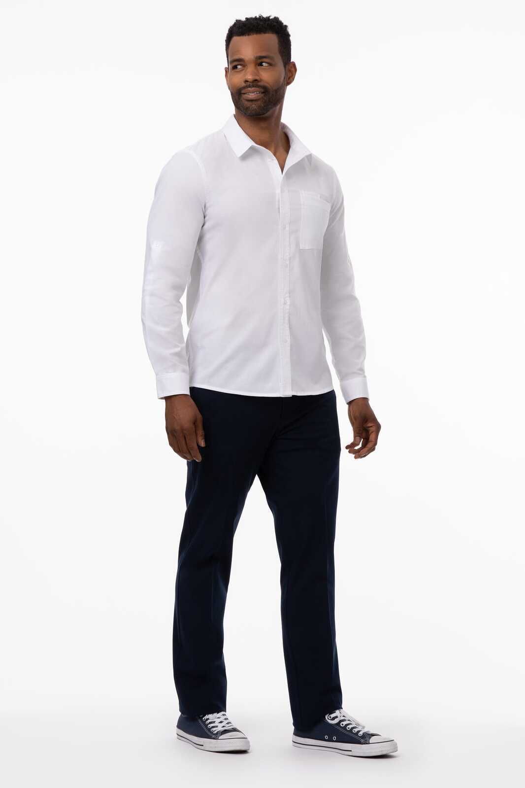 A man wearing a classic blue button-up shirt paired with dark trousers and casual shoes. The shirt features a logo.