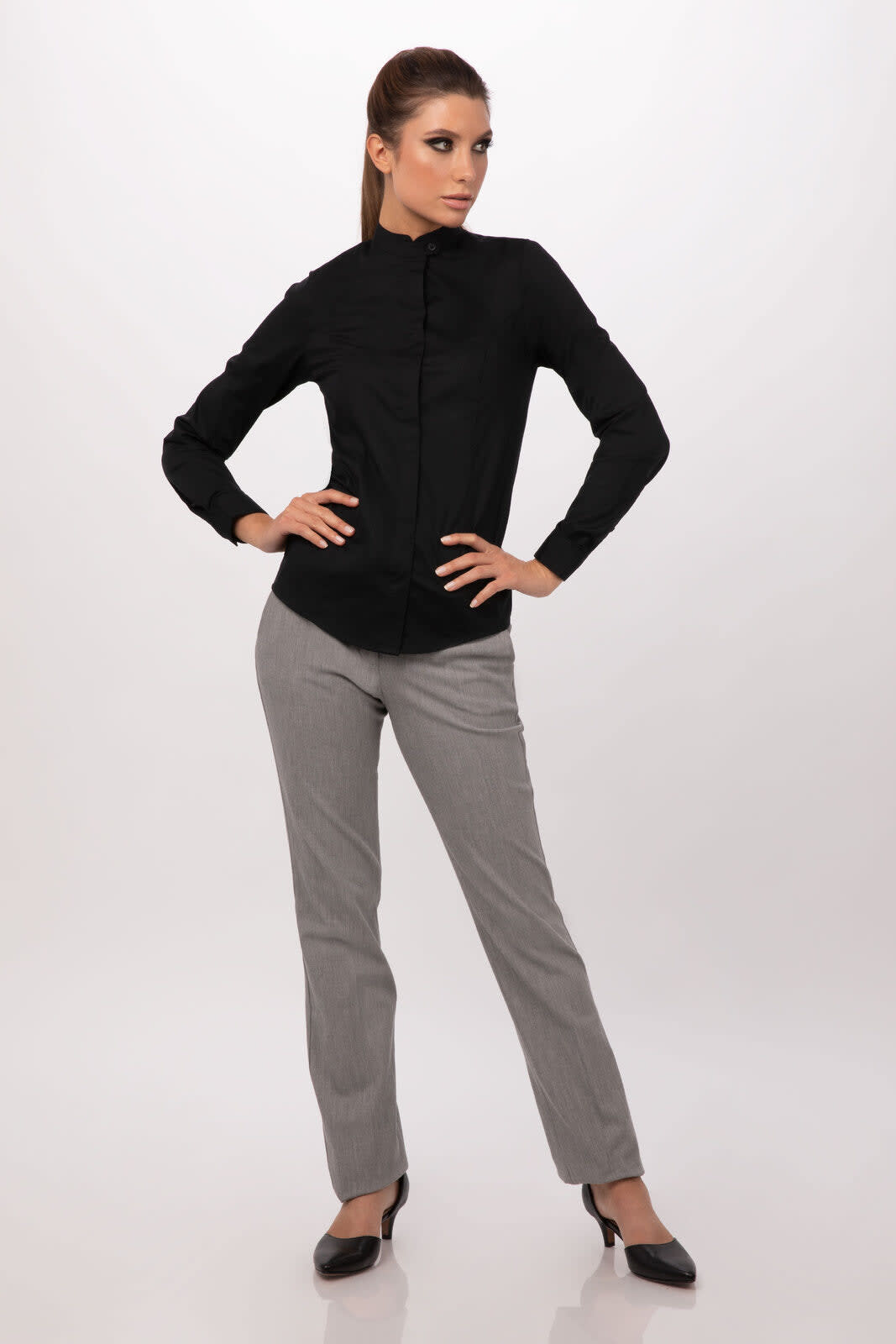 A black button-up women's shirt displayed on a model, paired with grey trousers. The shirt features a collar and buttons.