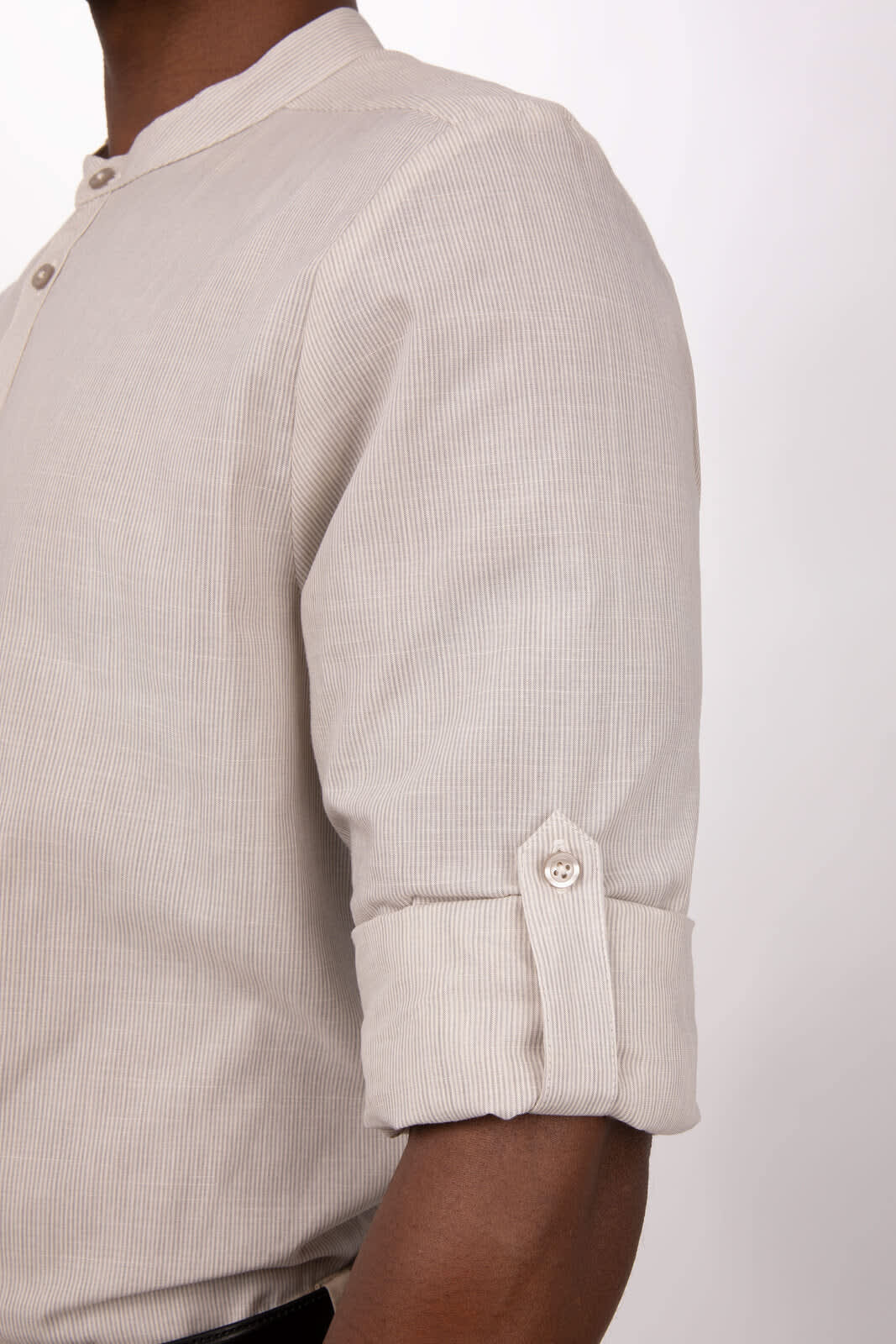 A light beige button-up shirt with rolled sleeves and a single button detail on the cuffs. Features a branding logo.