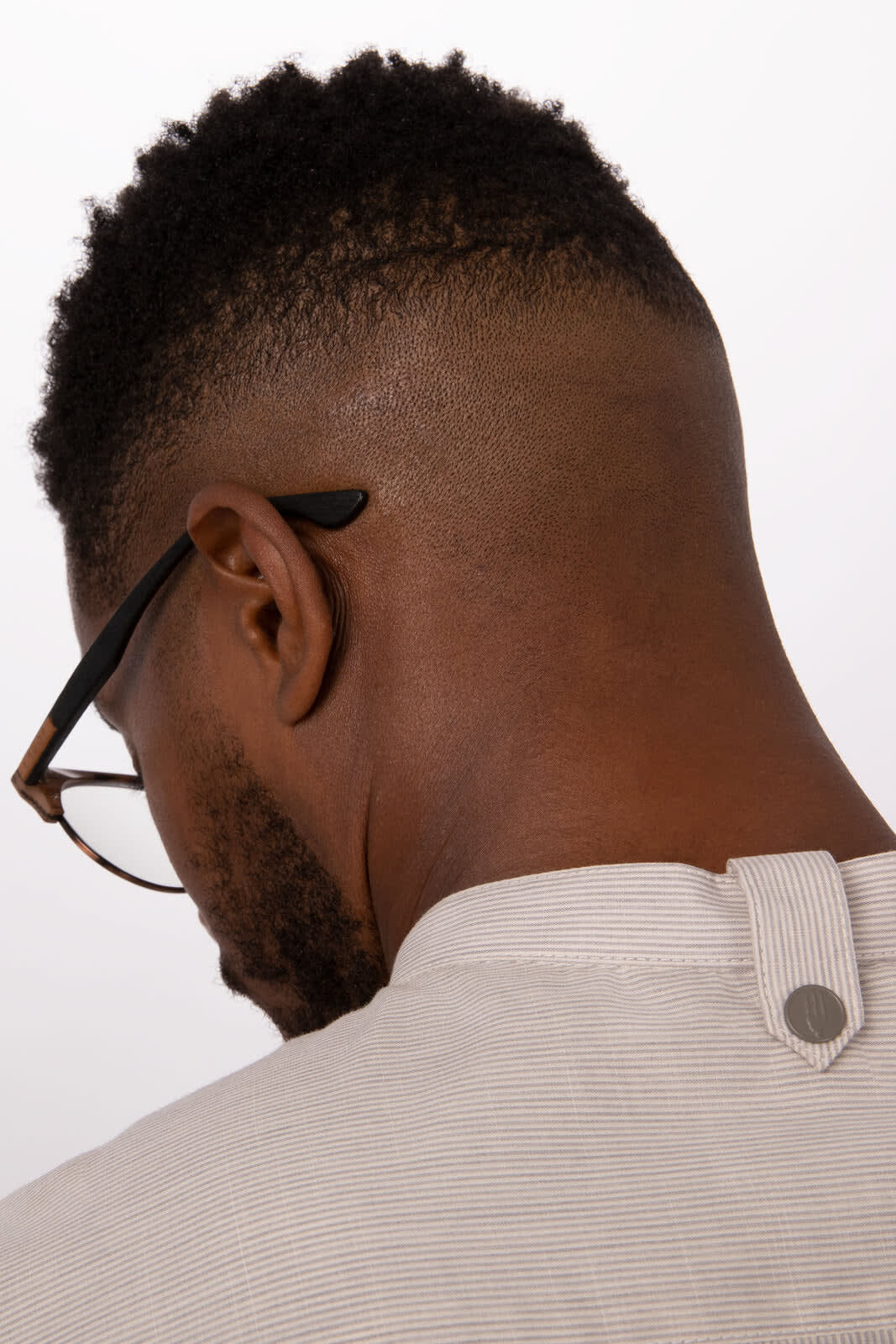A close-up of a button-up shirt in a light colour, featuring a stylish collar and a branded fastener at the back.