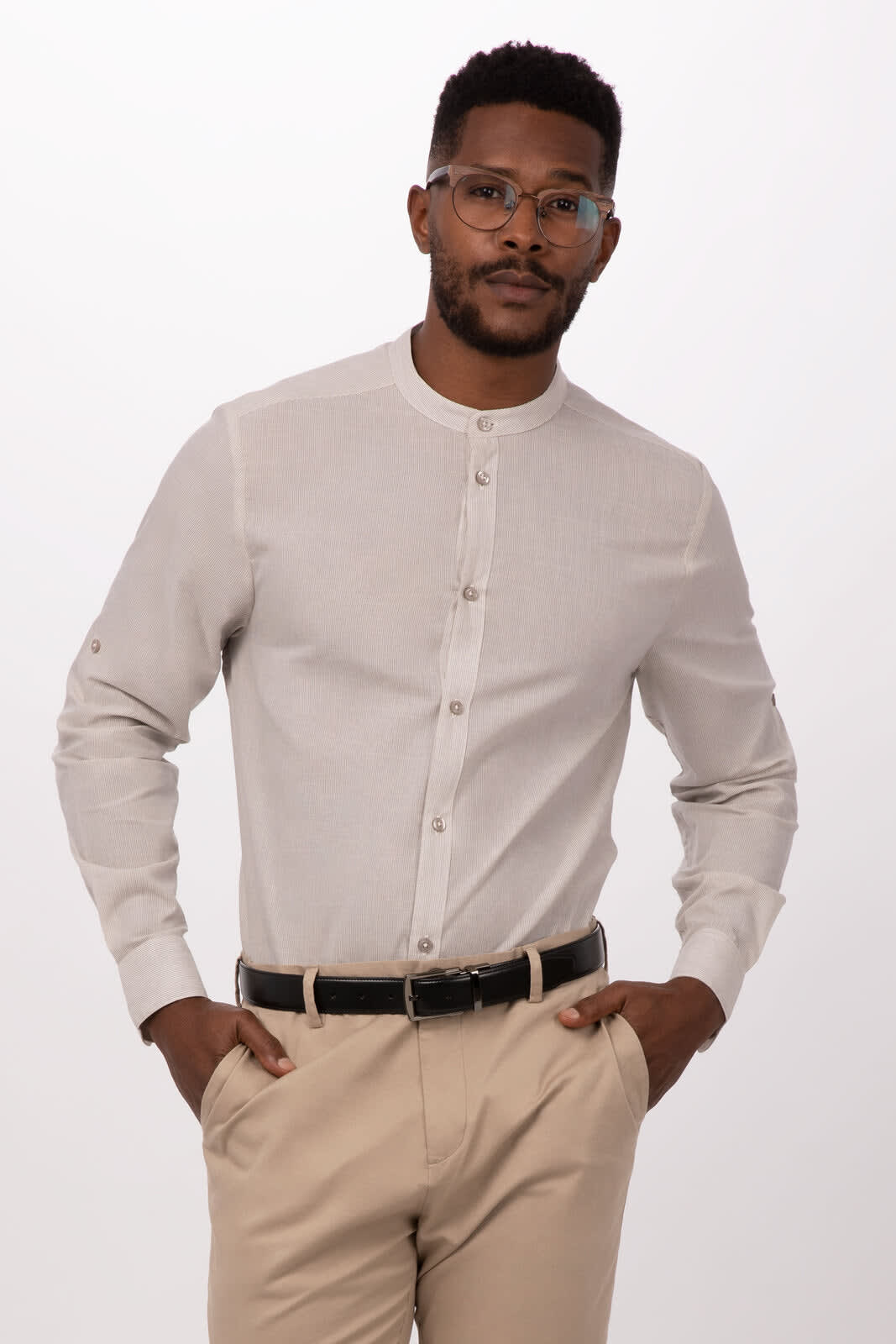 A light beige button-up shirt with a band collar, featuring a logo, displayed by a man wearing glasses.