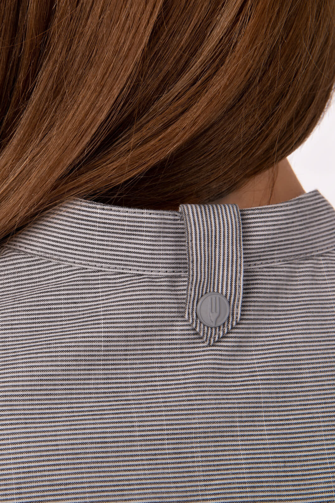 A grey and white striped button-up shirt with a collar and a single button detail at the back.