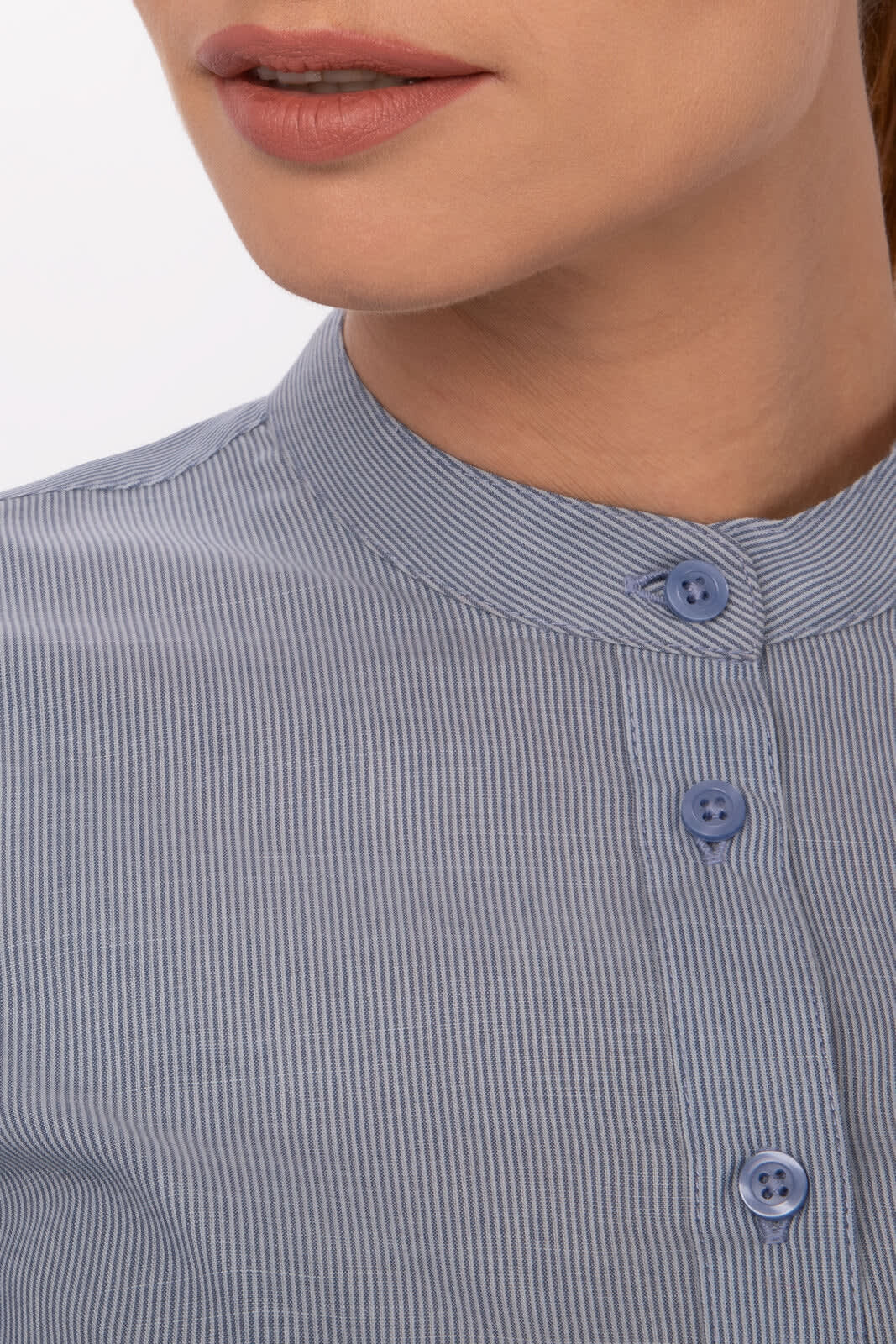 A close-up of a women's button-up shirt in light blue with a striped pattern and a stand collar. It features blue buttons.