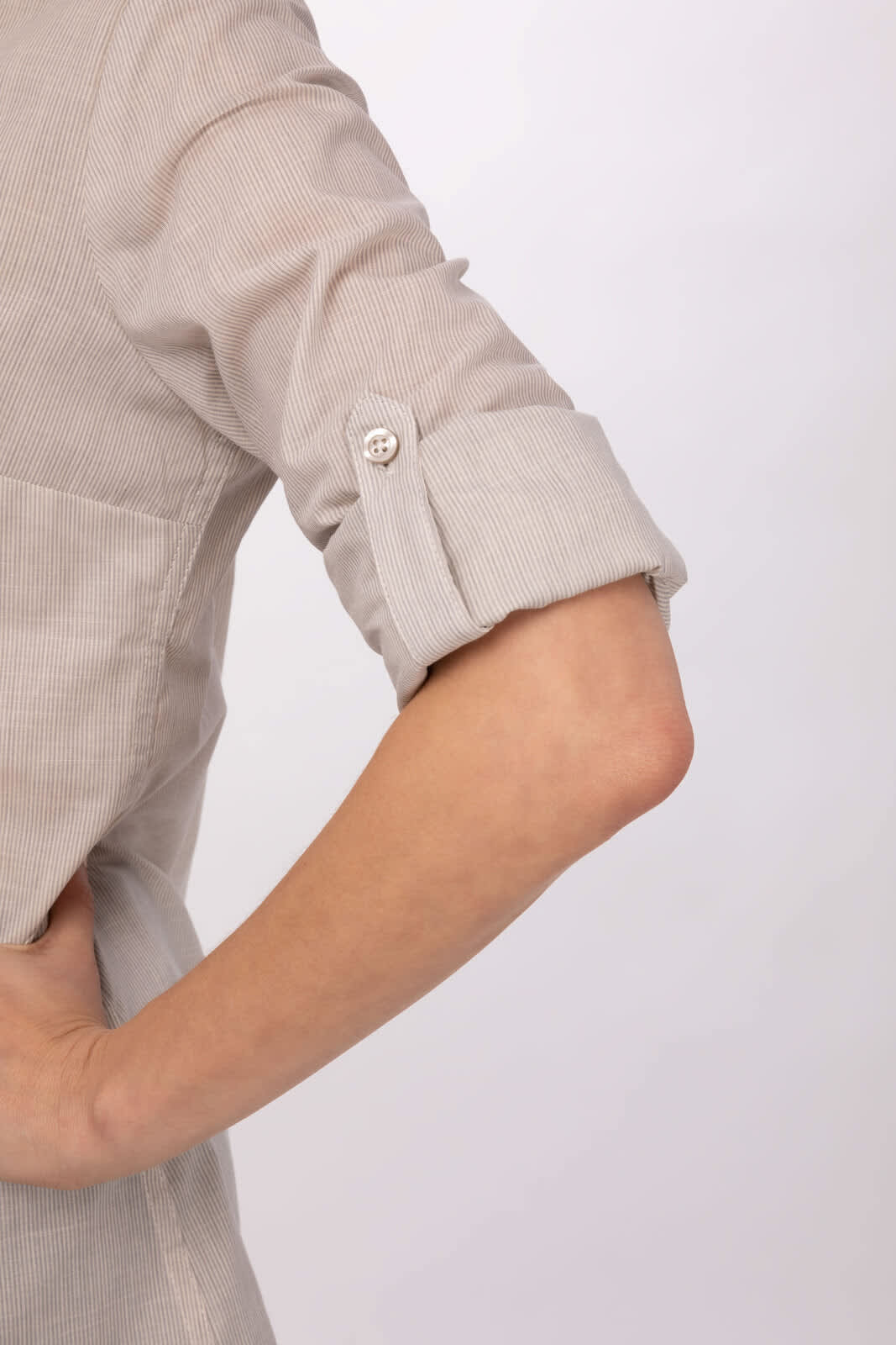 A rolled-up sleeve of a light grey button-up shirt with a button detail. The fabric appears textured.