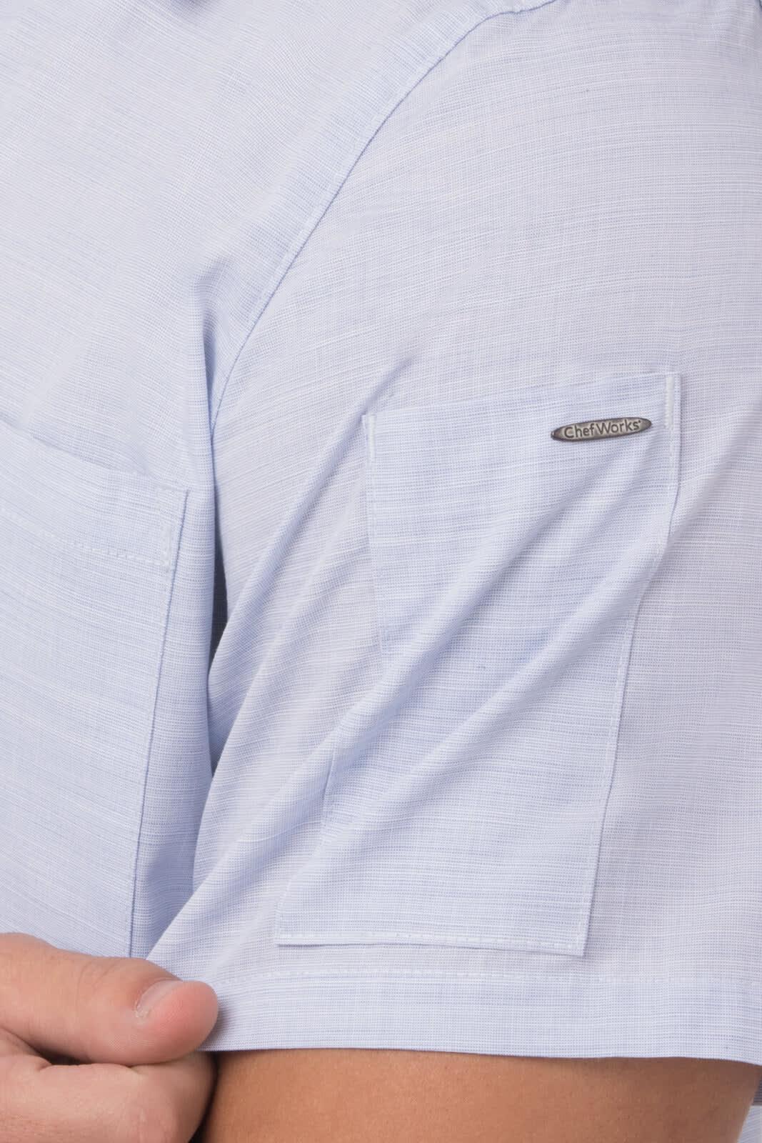 A light blue men's shirt with chest pockets and a logo on the sleeve.