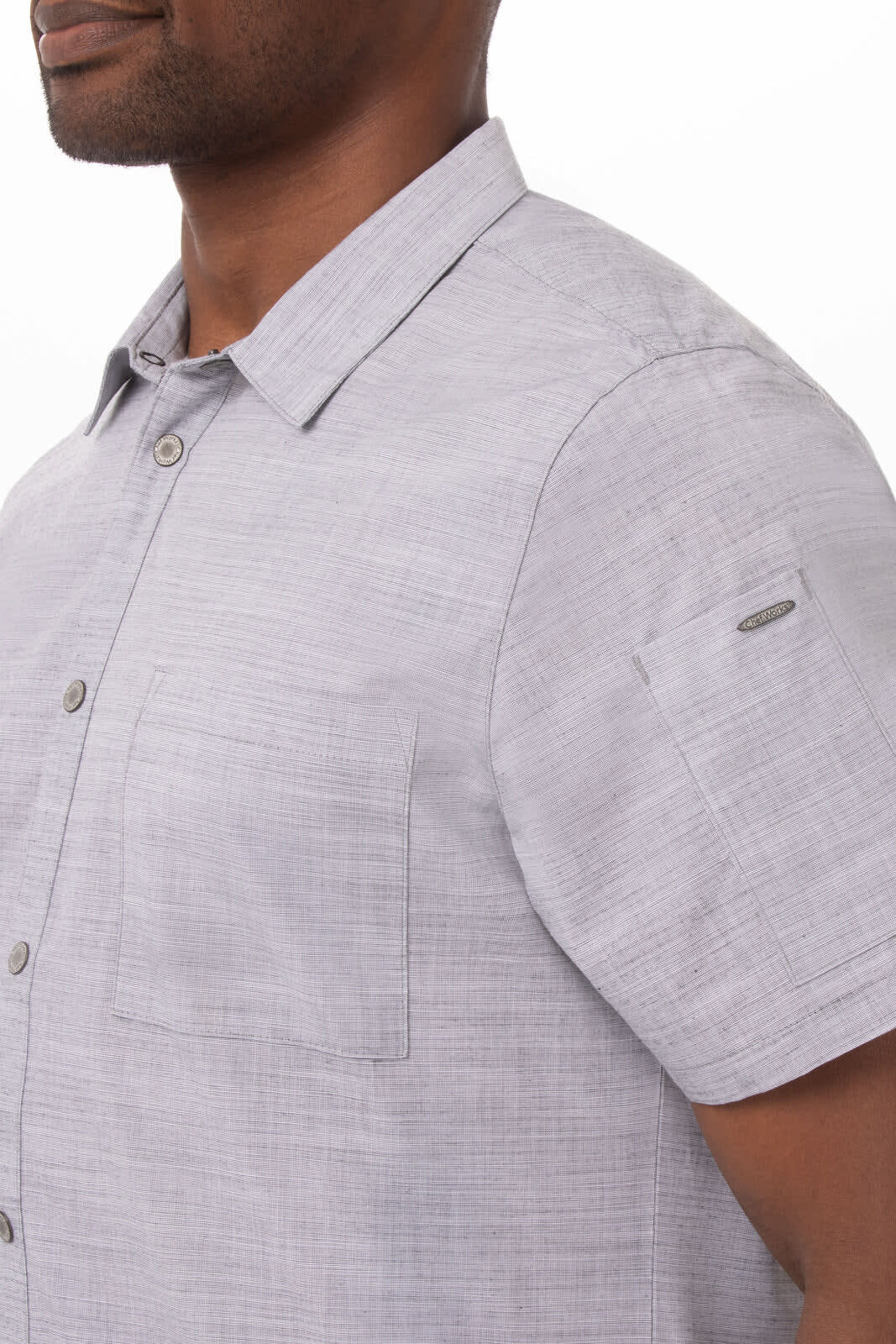 A men's short-sleeve shirt in light grey, featuring two pockets and a logo on the sleeve.