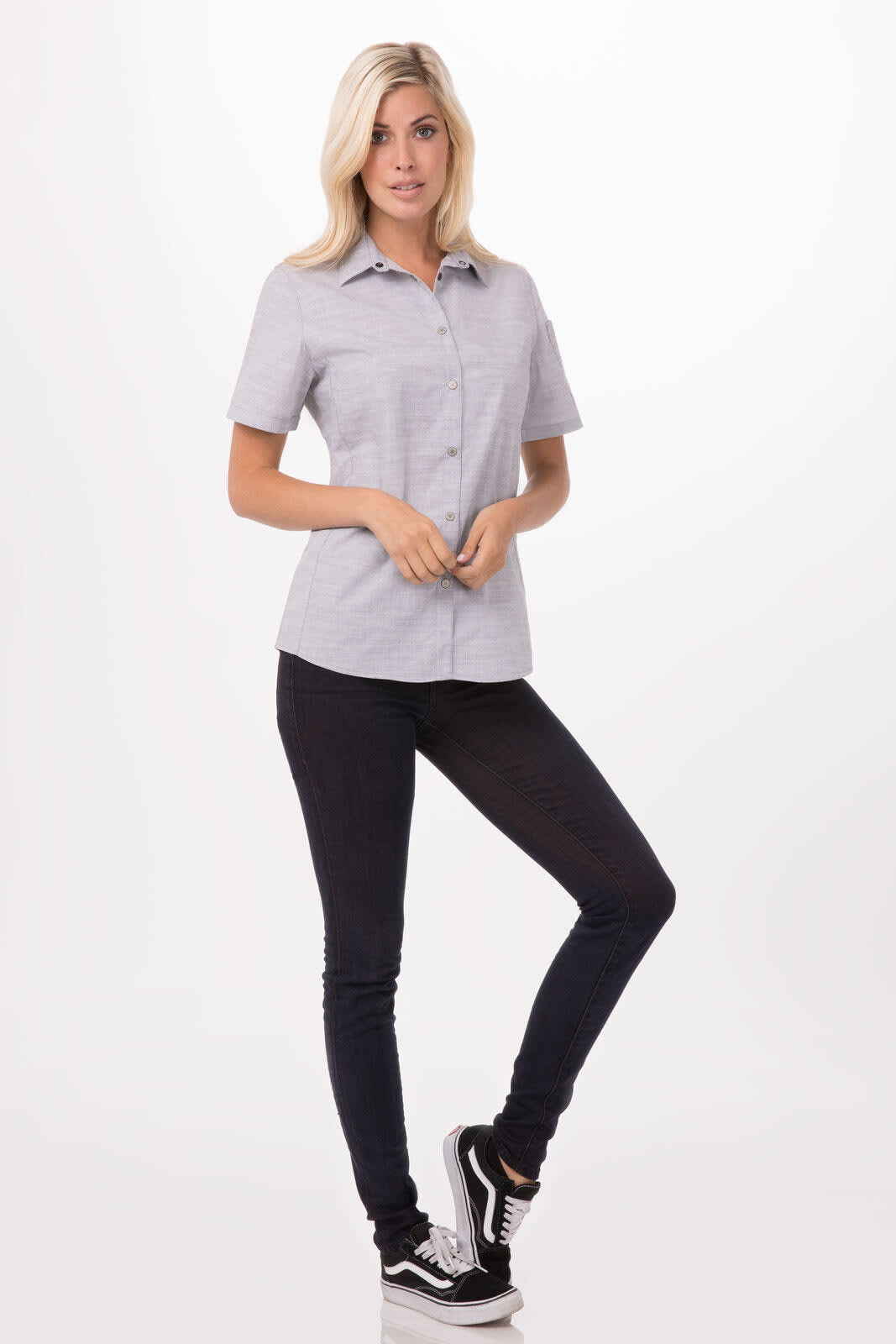 A short-sleeved button-up shirt in grey with a collar, worn with dark jeans and black sneakers. Features branding.