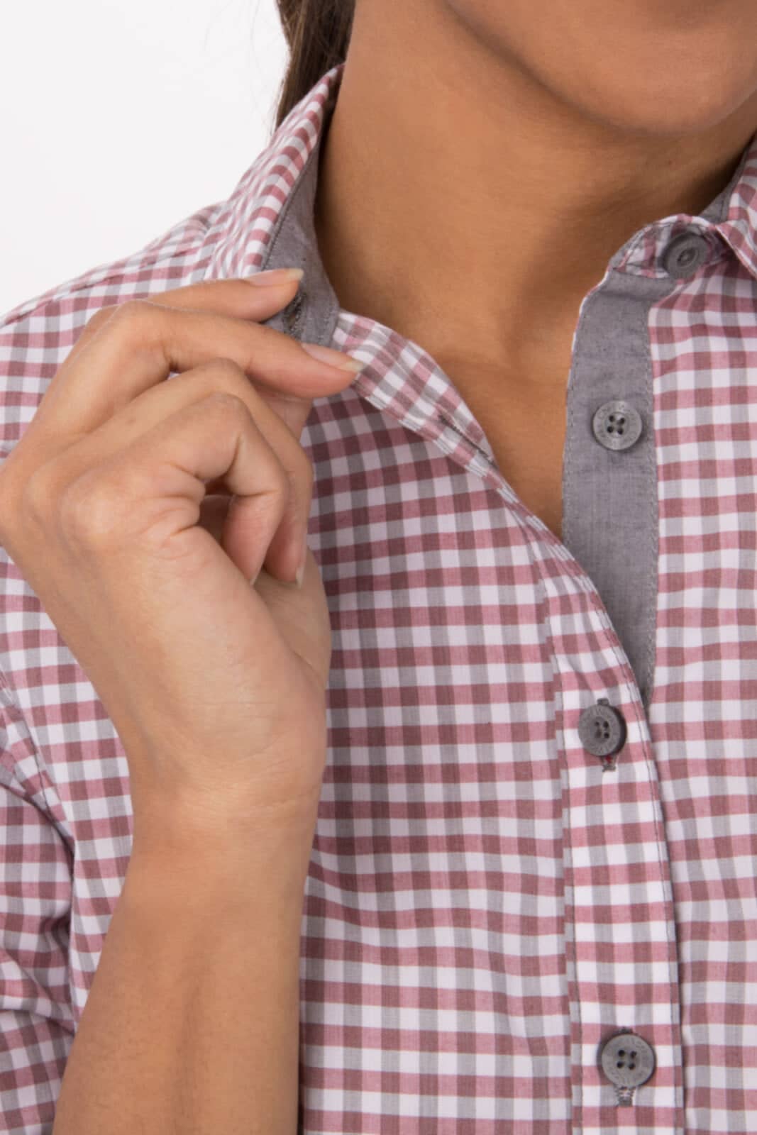 A close-up of a women's long sleeve dress shirt featuring a modern gingham pattern in pink and grey hues with a branded logo.