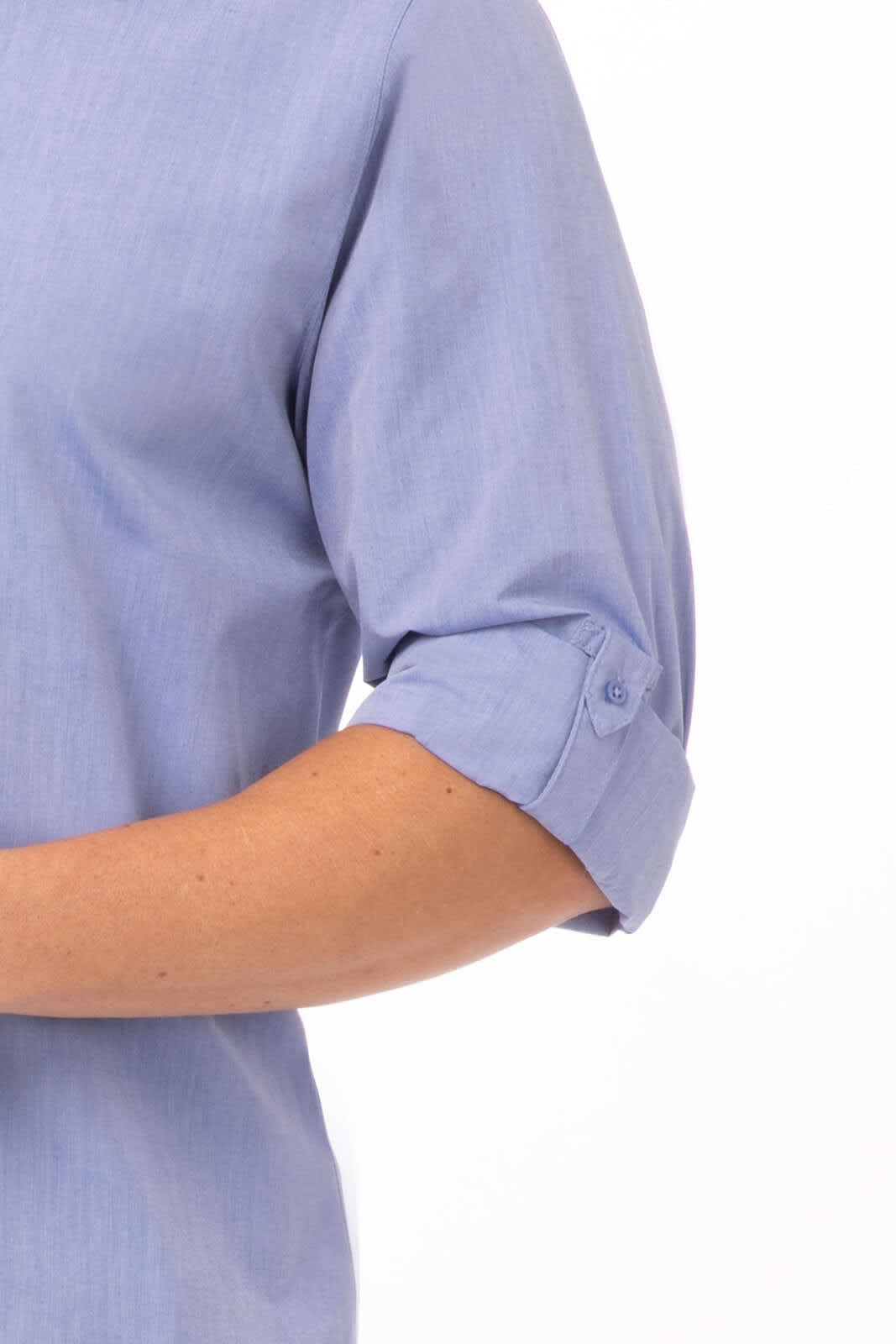 A modern chambray men's dress shirt in light blue, featuring rolled sleeves and a button detail.
