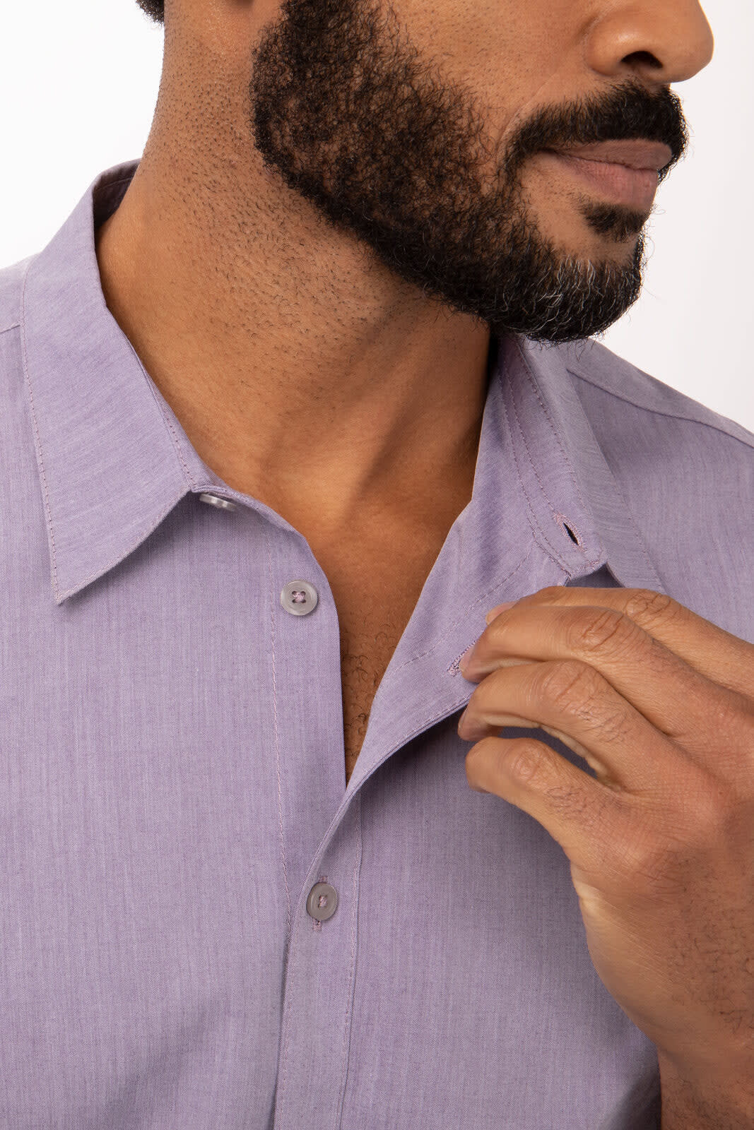A close-up of a man's dress shirt in light purple chambray, featuring a button-up collar and a subtle logo.