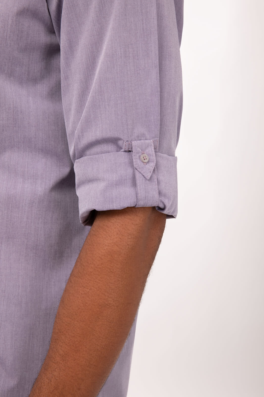 A modern chambray men's dress shirt in light purple, featuring rolled sleeves and a buttoned cuff.
