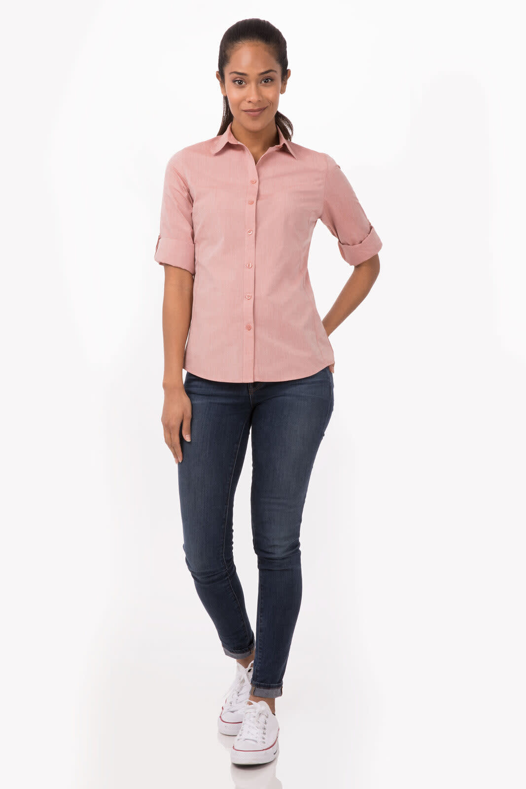 A pink chambray women's button-up shirt paired with fitted jeans and white sneakers, featuring rolled sleeves.