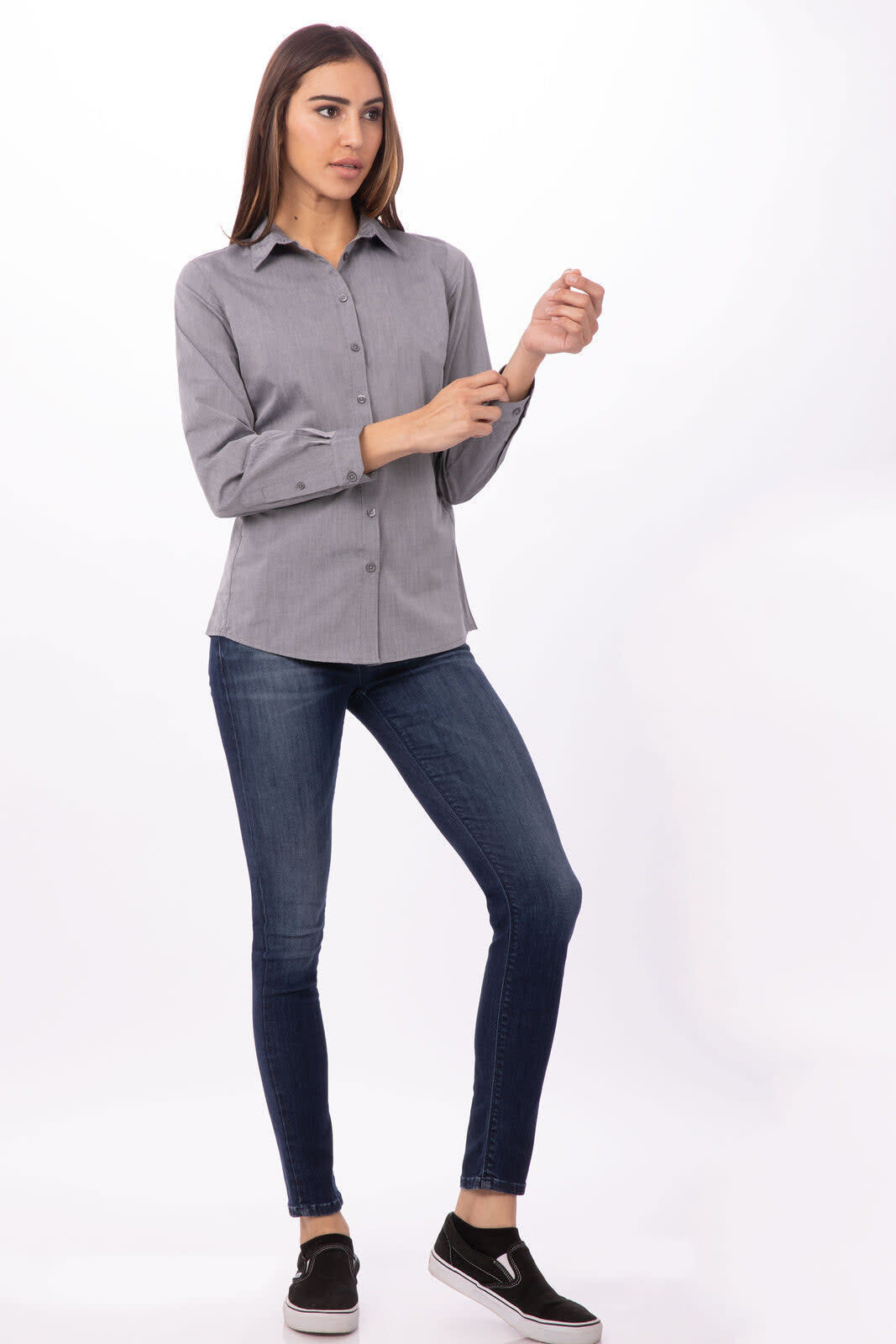 A grey chambray button-up women's dress shirt paired with blue jeans and black slip-on shoes.