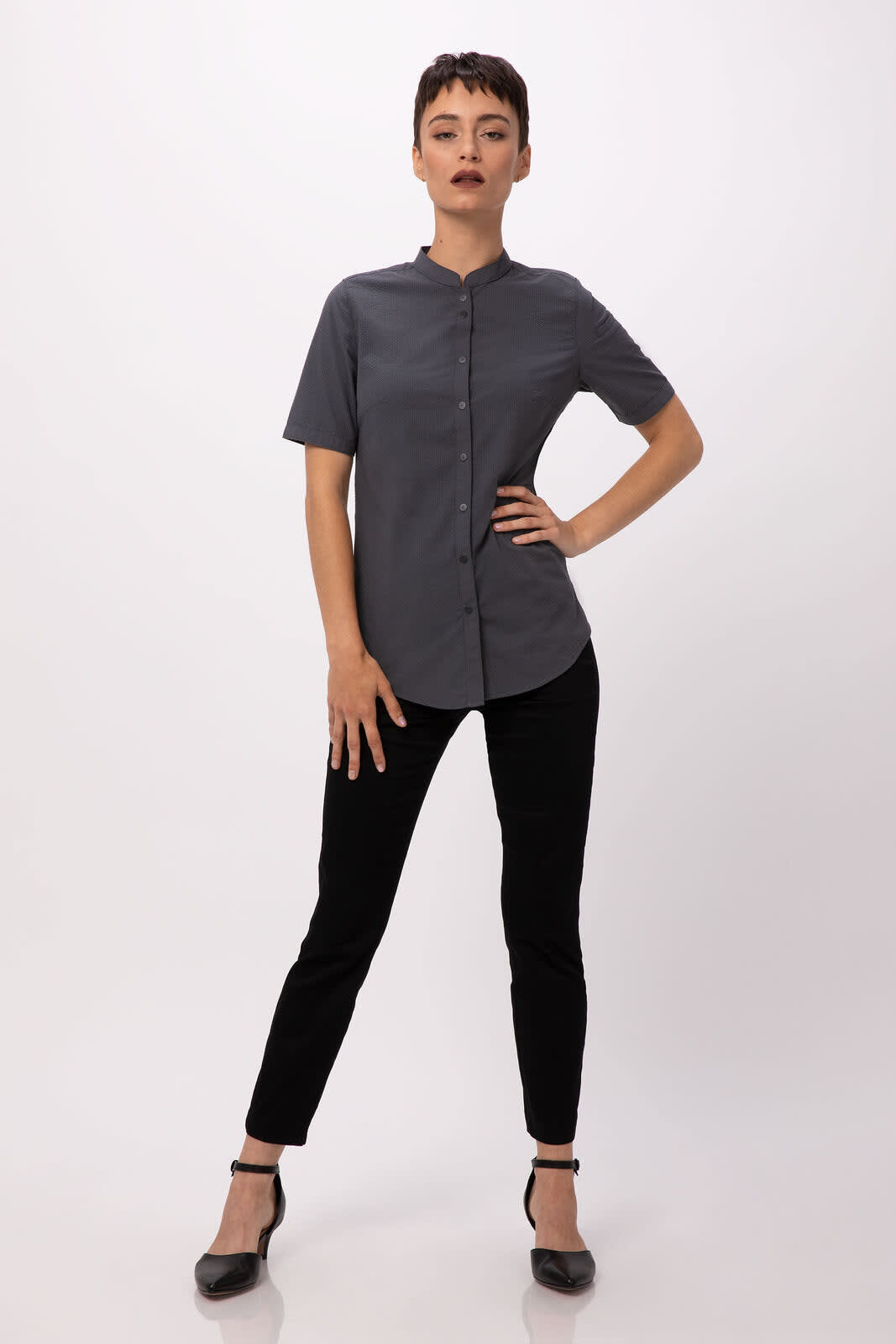 A short-sleeved button-up shirt in grey, paired with black trousers and heels, featuring a simple design and collar.