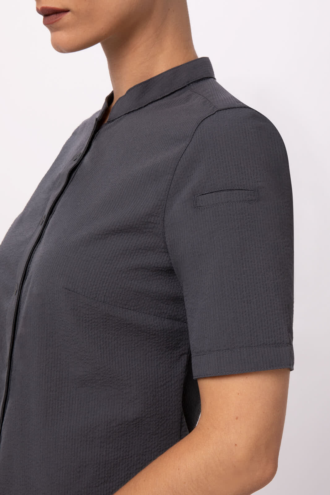 A grey seersucker women's button-up shirt with a short sleeve and a collar, featuring a subtle texture.