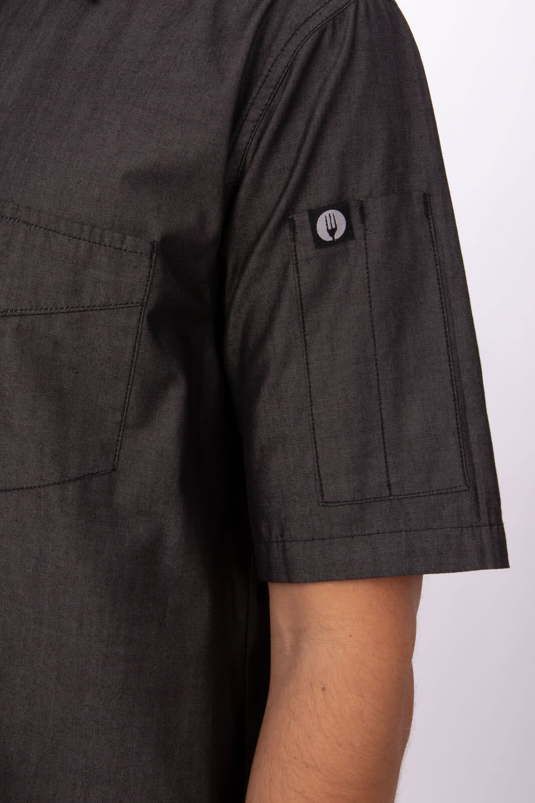 A dark grey short sleeve denim shirt featuring a buttoned pocket and a small logo on the sleeve.