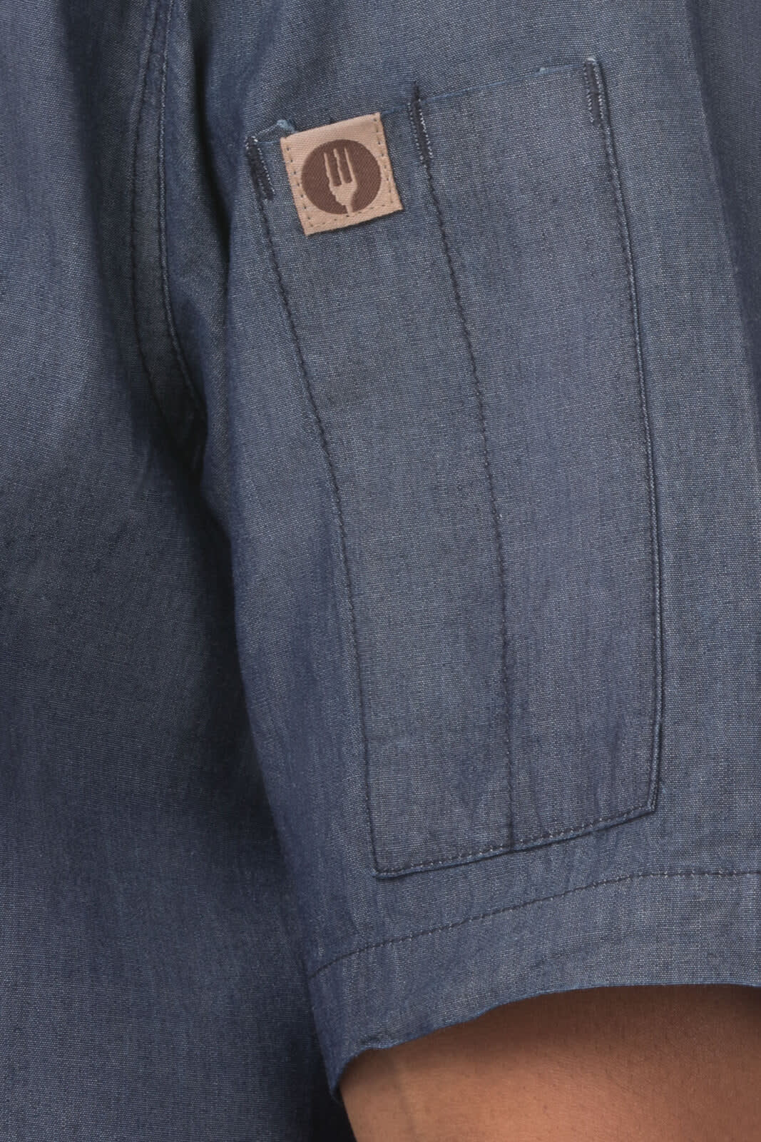 A denim shirt in blue with short sleeves and a small logo on the sleeve.