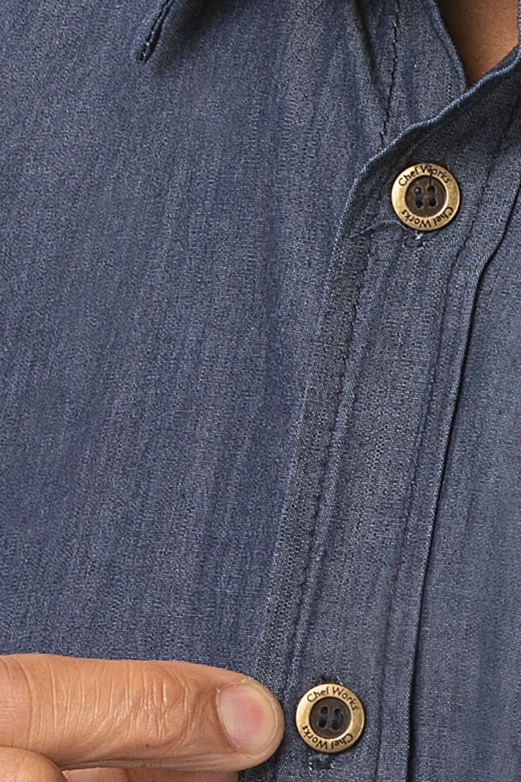 A close-up of a blue denim button-up shirt featuring brass buttons and a soft fabric texture.