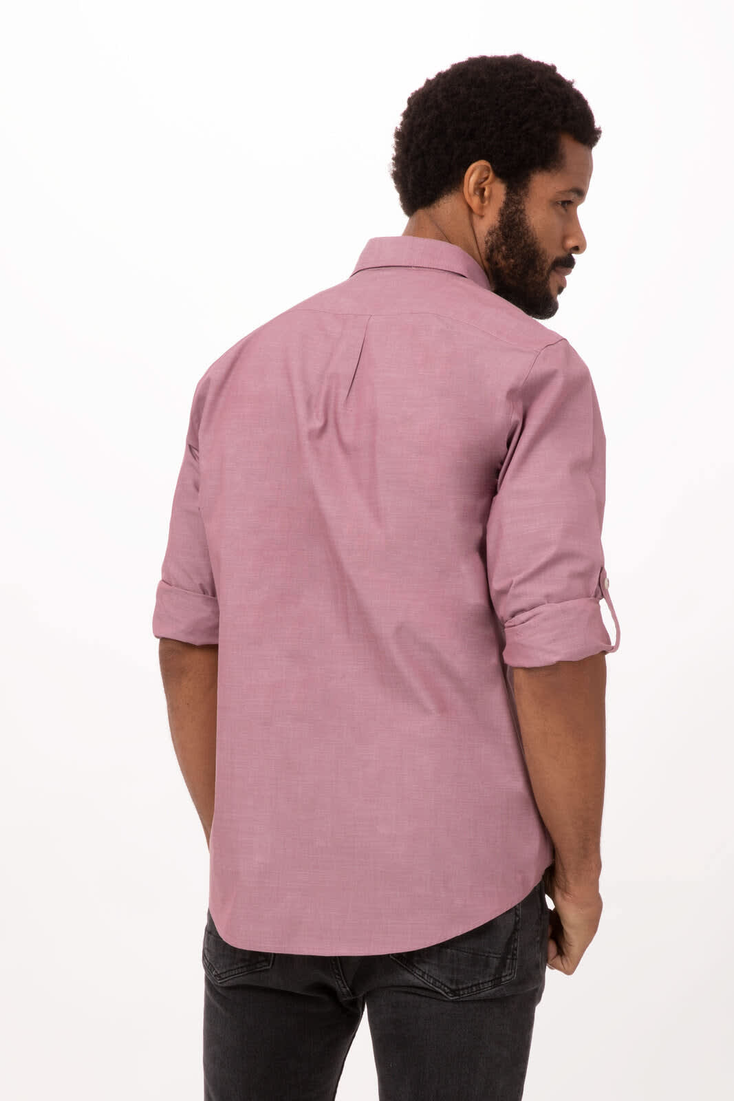 A men's button-up shirt in a soft pink hue, featuring rolled sleeves and a casual fit. The shirt has a subtle branding logo.