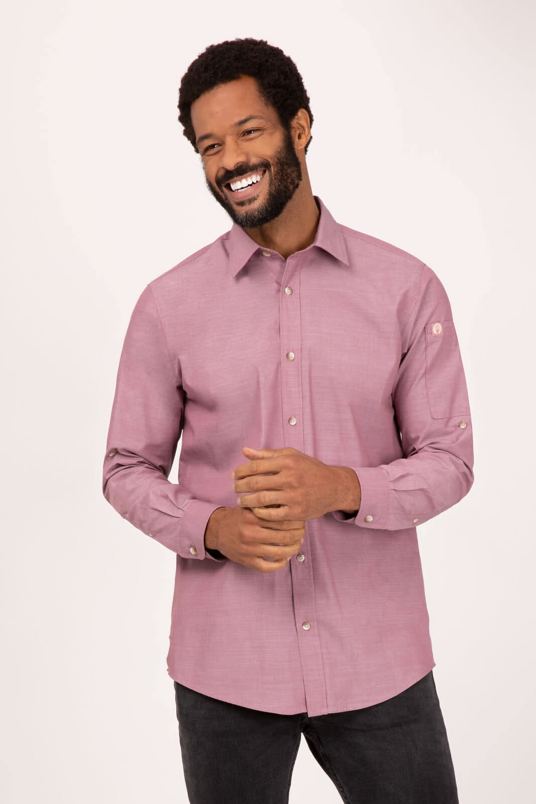 A man wearing a long-sleeve, button-up shirt in a muted burgundy colour, featuring a logo on the sleeve.