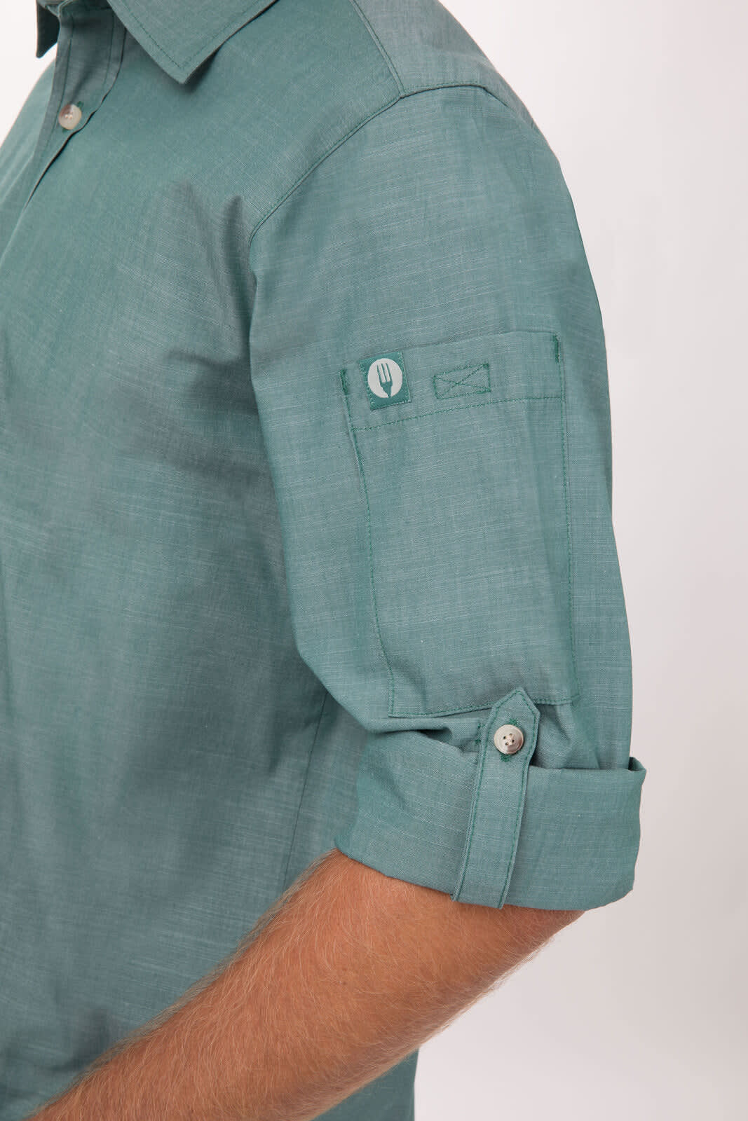 A chambray men's shirt in a teal hue, featuring rolled-up sleeves and a buttoned cuff detail.