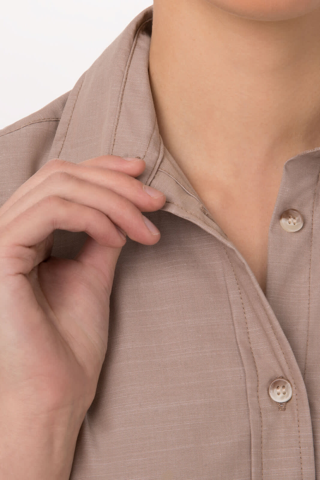 A close-up of a woman's chambray shirt in a soft beige colour, focusing on the collar and buttons.