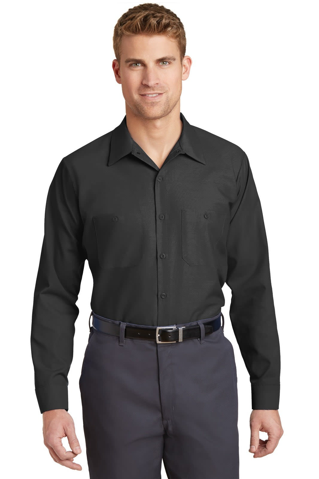 A man wearing a long sleeve black industrial work shirt, paired with dark trousers and a belt. The shirt features a logo.