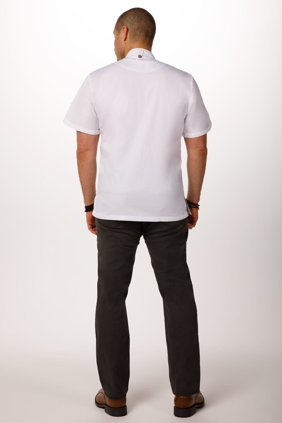A chef jacket in white, featuring short sleeves and a back view, worn with dark trousers. The jacket has a logo.