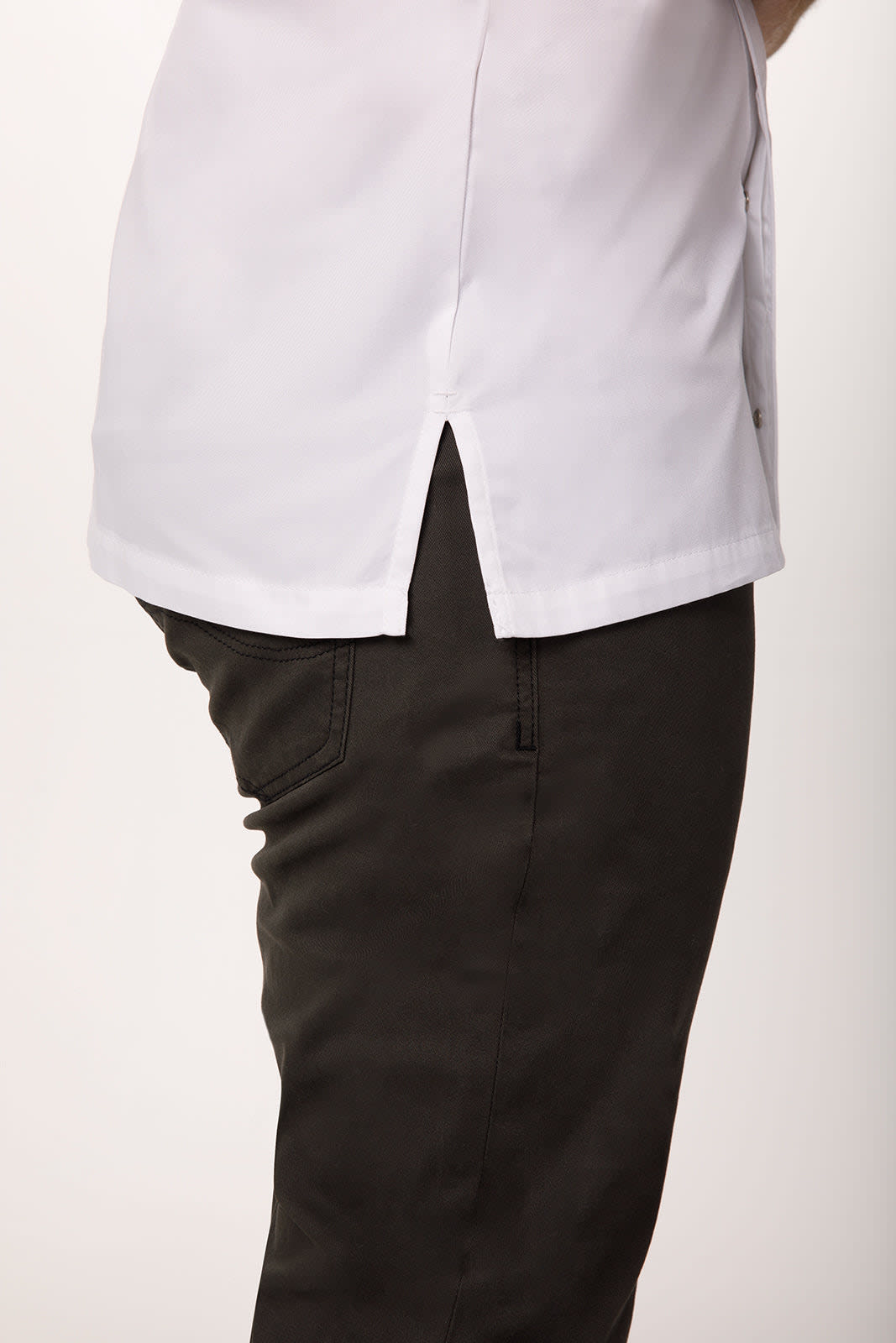 A white chef jacket featuring a split back, paired with dark trousers. The jacket has a simple design and an incorporated logo.
