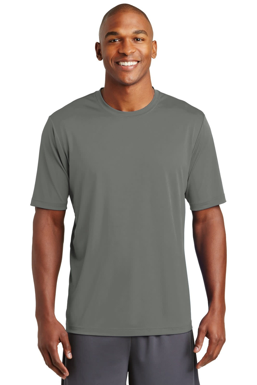 A man in a grey sports t-shirt stands smiling, featuring short sleeves and a crew neck design.
