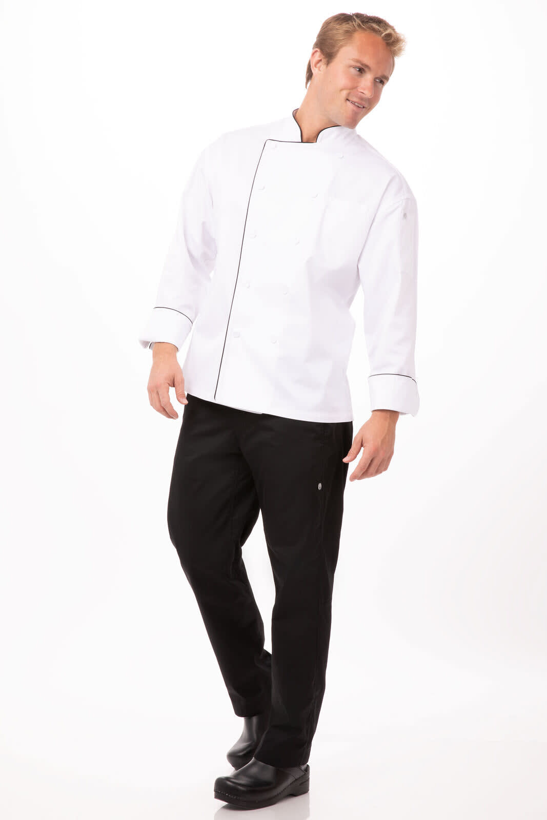 A man wearing a white executive chef jacket with black trim and black pants, looking casually to the side.