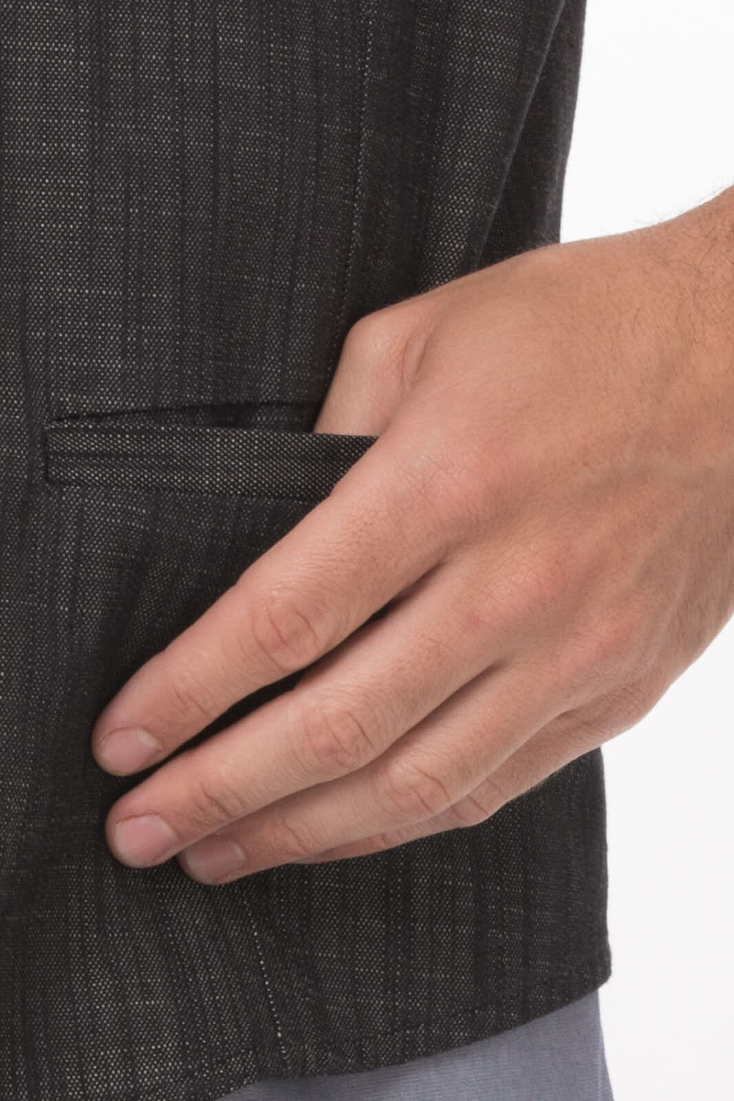 A close-up of a hand in the pocket of a dark grey, textured men's vest. The vest has a subtle pattern and logo.