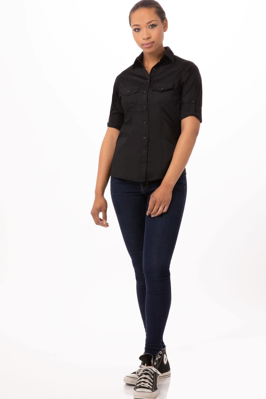 A black button-up women's shirt with short sleeves, featured alongside fitted blue jeans and sneakers.