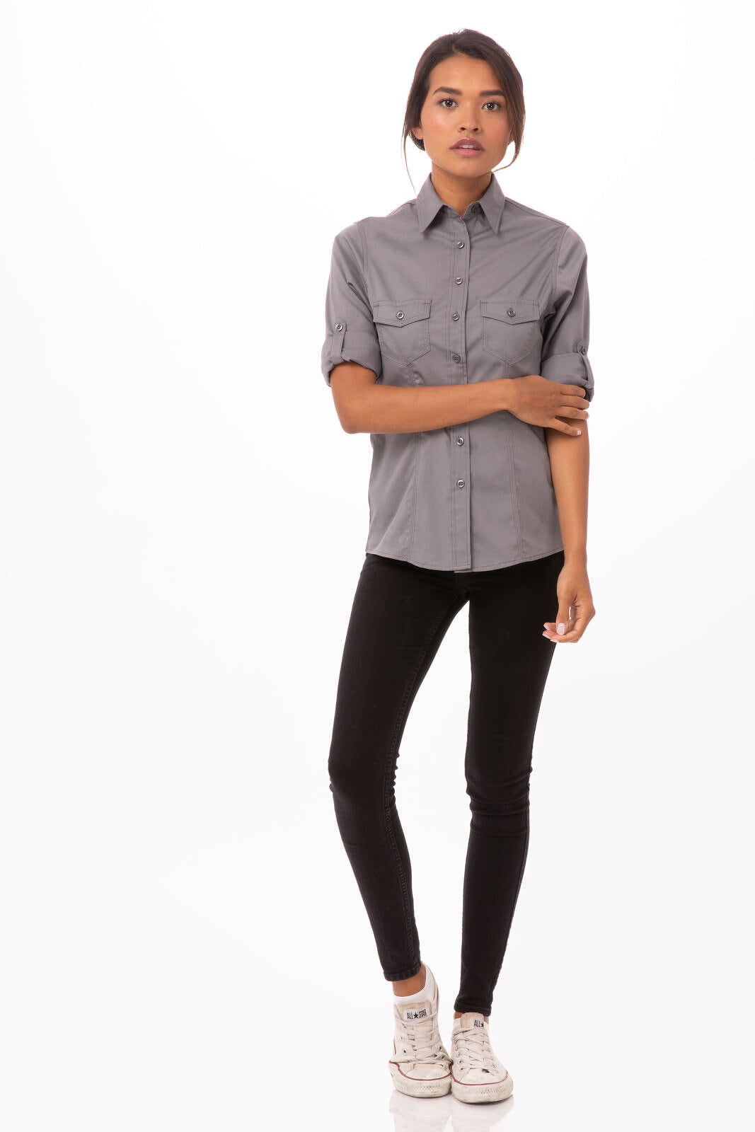 A grey button-up shirt with short sleeves and two front pockets, worn by a model with dark hair and casual trousers.