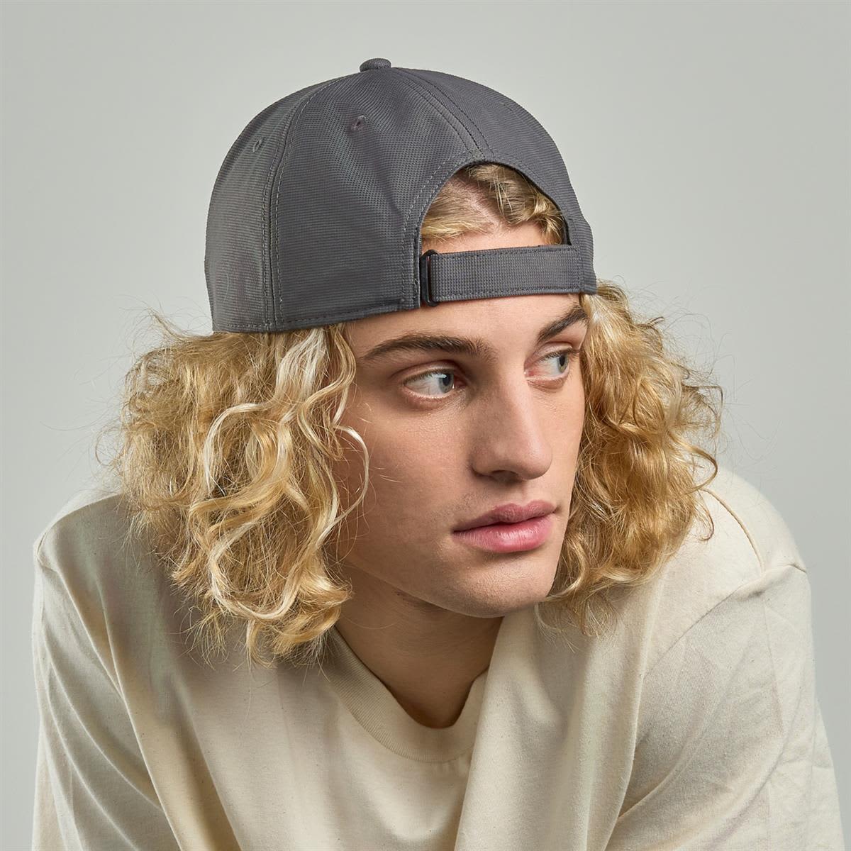 Estoril-S Cap - Recycled Polyester LE-A1310 A cap made from recycled polyester in grey, worn by a model with curly blonde hair. It features a logo on the front.