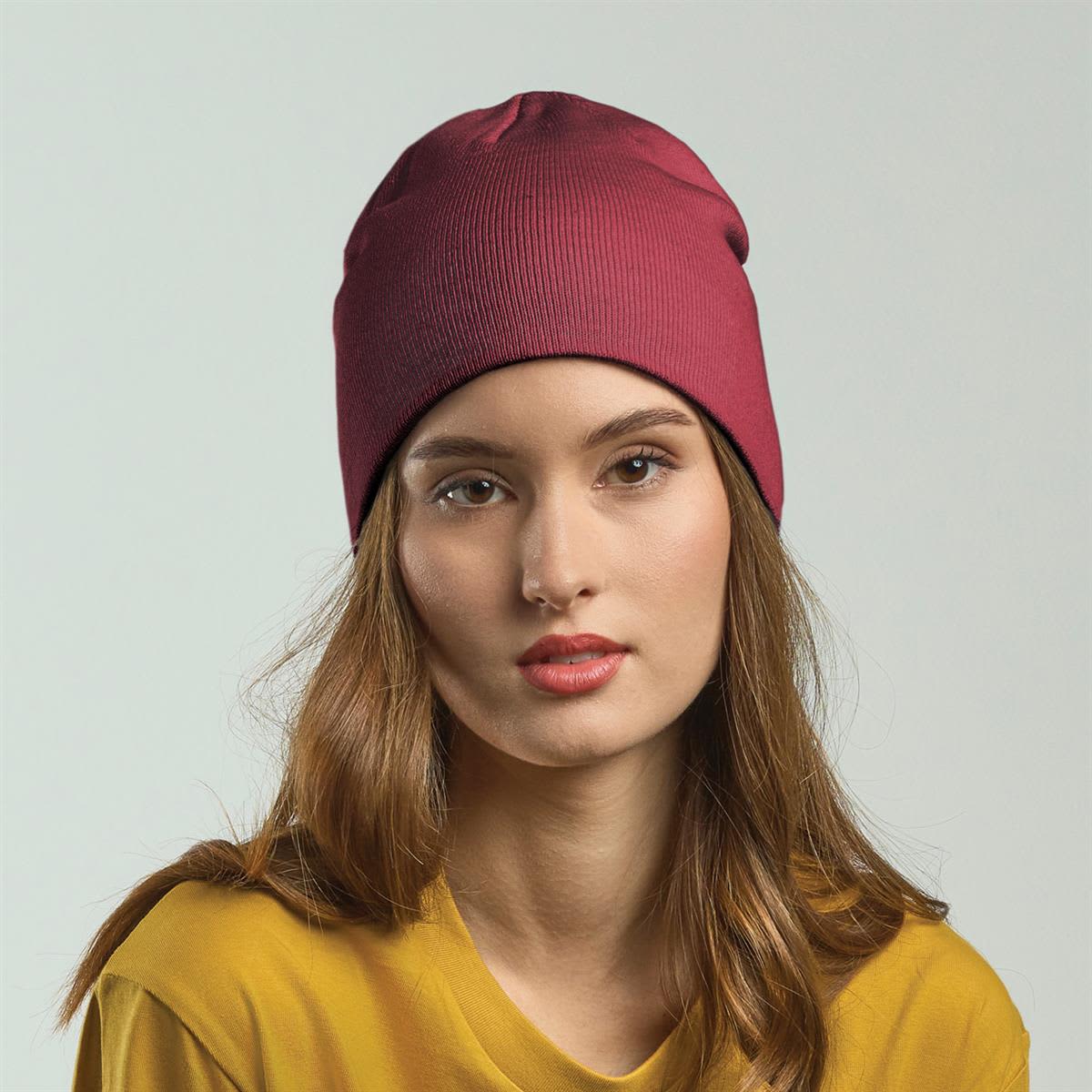 Holly Polylana Beanie LE-A4570 A maroon beanie worn by a model with long hair, paired with a yellow top, featuring a branding logo.
